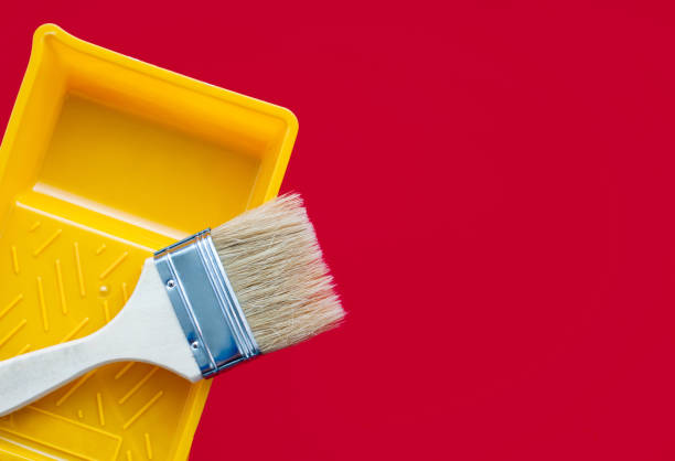istock Clean paint brush and yellow plastic paint tray on a red background. Copy space 1257942178