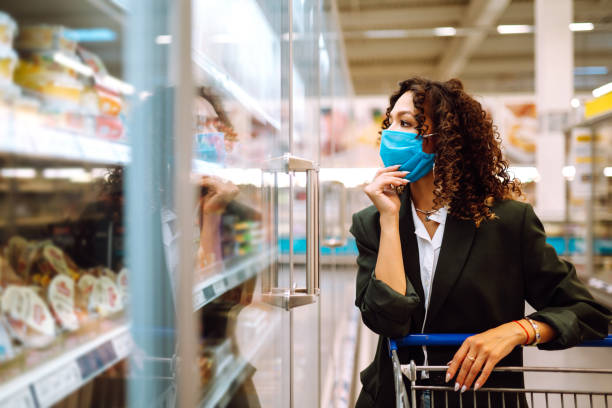 istock Young woman wearing face mask buying in supermarket. 1257943708
