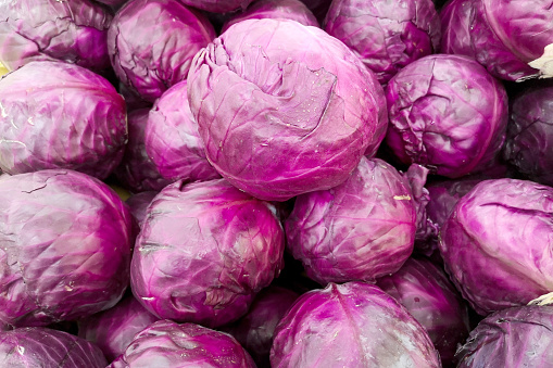 A group of red cabbage on retail display.