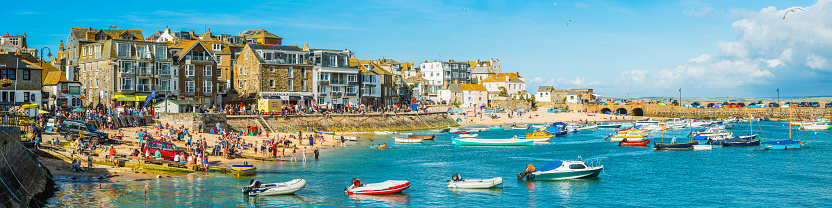 Crowds of holiday makers, day trippers and tourists enjoying the summer sunshine on the popular harbour beach of St. Ives, Cornwall.