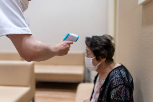 infirmière masculine mesurant la température corporelle d’une femme âgée avec le thermomètre numérique, défocused - thermometer cold fever focus photos et images de collection