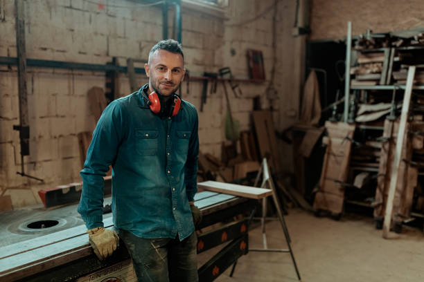 He's got a passion for small business Portrait of Carpenter in His Workplace in Carpentry Workshop Looking at Camera. Profession, Carpentry, Woodwork and People Concept. Small Business Owner freelance work stock pictures, royalty-free photos & images