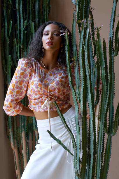 Gorgeous fashionable a female model among cactuses.