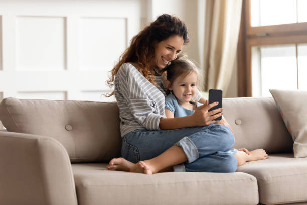 istock Smiling mother and little daughter hugging, using phone together 1257955476