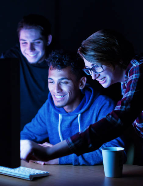 istock Group of young male and female tech workers collaborating as they interact with a computer at night 1257957329