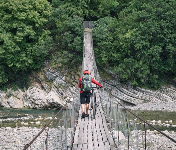 istock Man with bike on suspension bridge 1257957981