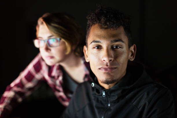 Young man and woman working at a night on a computer reflected in her glasses