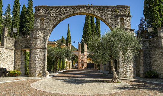 Gardone Riviera, Lake Garda, Italy - September 2018:  View from the road of the arched entrance to the Vittoriale degli Italiani gardens in Gardone Riviera. The gardens include an amphitheatre where performances are held.