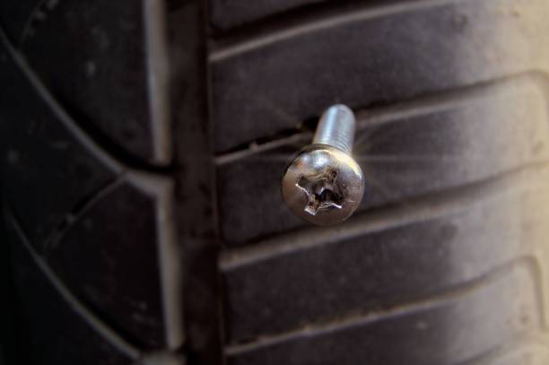 Leaked car tire by stabbed silver round screw nail