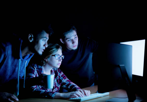 istock Group of young male and female tech workers collaborating as they interact with a computer at night 1257961225
