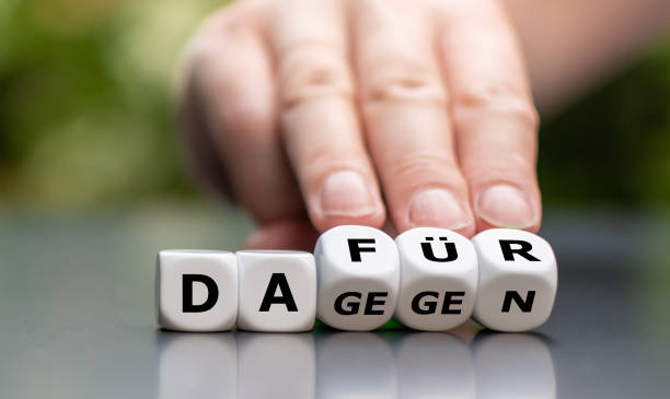 Hand turns dice and changes the German word "against" (cons) to "dafuer" (pros) Hand turns dice and changes the German word "dagegen" (cons) to "dafuer" (pros) pros and cons stock pictures, royalty-free photos & images