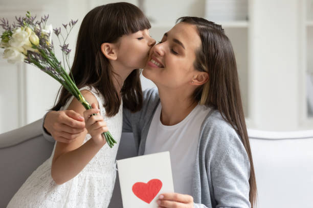 istock Little daughter congratulate excited young mom presenting flowers 1257964396
