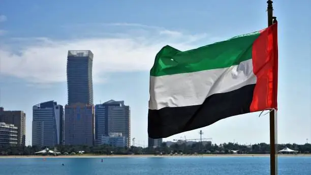 Photo of Close up view on UAE national flag by skyscrapers