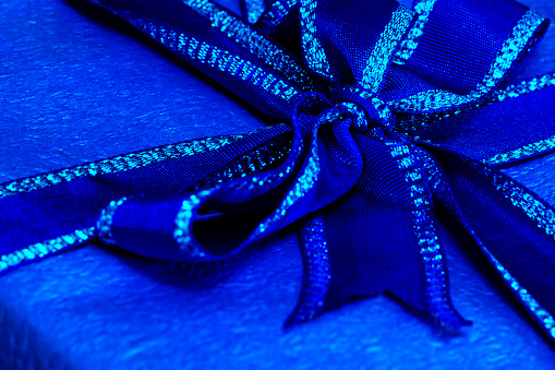 Close-up of a blue gift box with ribbon and bow.