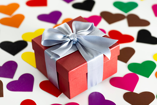A red gift box is on the colored heart shapes.