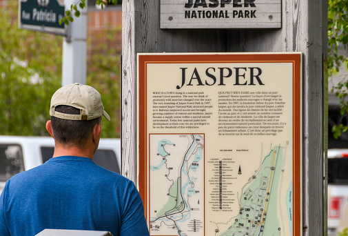 Jasper, Alberta, Canada - June 2018: Visitor to Jasper studying a map of the Jasper national park area. The town is a popular tourist destination.