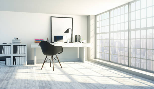 Modern home office interior Interior of a modern home office next to a big window. Light wood desk with organized set up of books, office supplies and computer with some room decor around it. small office interior stock pictures, royalty-free photos & images