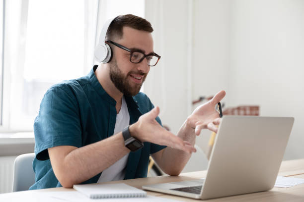 hombre de negocios sonriente en auriculares mirando la pantalla del ordenador portátil viendo el webinar. - chill out audio fotografías e imágenes de stock