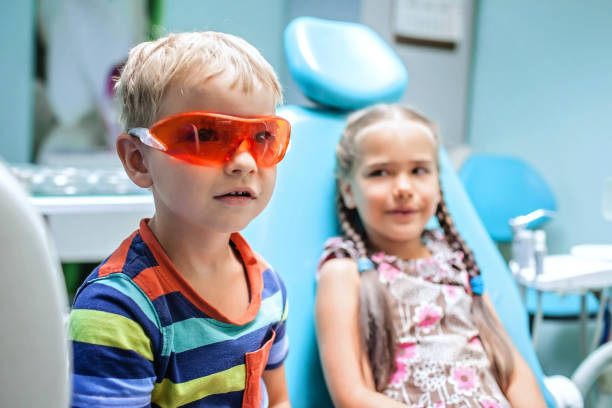 duas crianças se divertindo e usando óculos médicos durante visita ao consultório do dentista - baby boys clothing hospital simplicity - fotografias e filmes do acervo