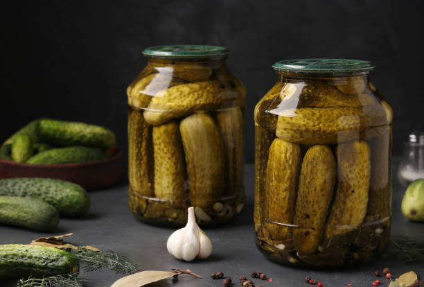 istock Marinated cucumbers in glass jars on a dark background, harvest for the winter, horizontal orientation 1257978069