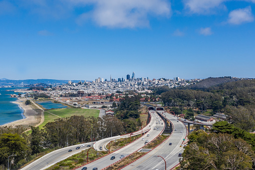 An aerial view of the San Francisco Skyline over the 101 freeway . Looking over Crissy Field, the Presidio and a few of the Bay Bridge.