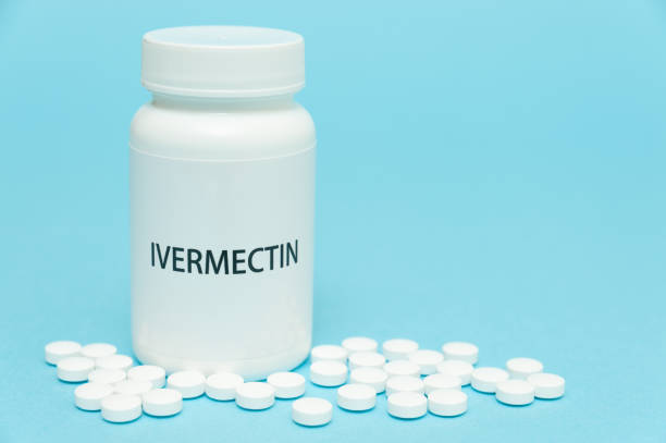 Treatments for Coronavirus (COVID-19): IVERMECTIN in white bottle packaging with scattered pills. Isolated on blue background. Horizontal shot. Copy space Treatments for Coronavirus (COVID-19): IVERMECTIN in white bottle packaging with scattered pills. Isolated on blue background. Horizontal shot. Copy space. world health organization photos stock pictures, royalty-free photos & images