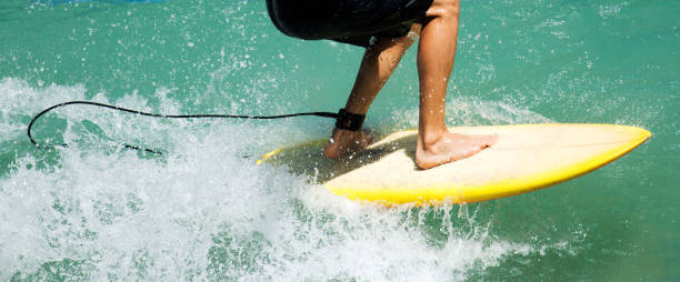 Surfers legs on yellow surfboard in aqua water