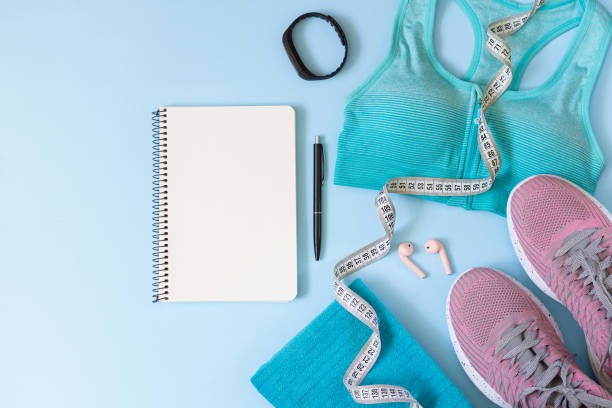 istock Workout plan concept. Stylish women's sport equipments, wear, gadgets and blank notepad from above 1257985376