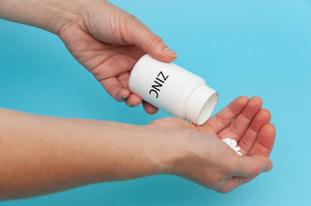 istock Treatments for Coronavirus (COVID-19): Zinc - White plastic packaging bottle in the hands with tablets. 1257985970