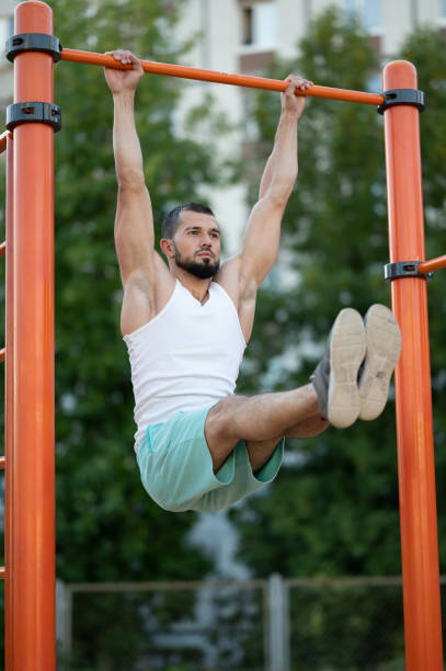 istock fitness, sport, exercising, training and lifestyle concept - man doing abdominal exercise on horizontal bar 1257986246