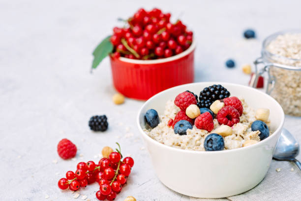 istock Oatmeal with raspberries, blueberries, blackberries, red currants and nuts on a gray concrete background. Healthy healthy breakfast. 1257996089