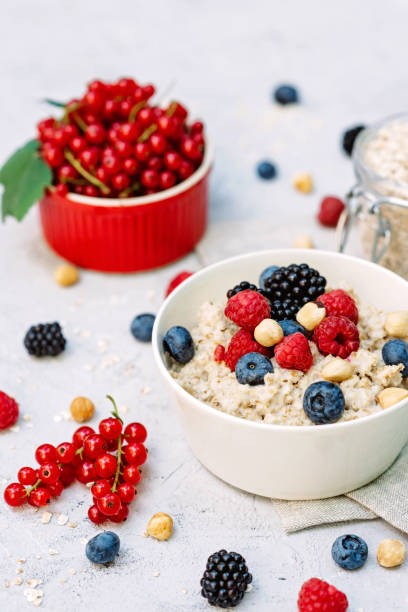 istock Oatmeal with raspberries, blueberries, blackberries, red currants and nuts on a gray concrete background. Healthy healthy breakfast. 1257996093
