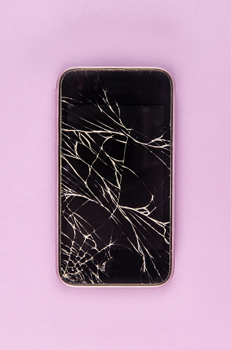 Broken smart phone on the pink paper background.