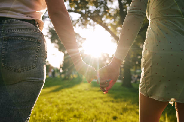 istock Modern lesbian couple holding hands while walking at a park 1258002569