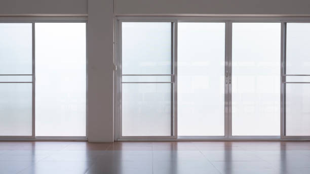 frosted glass sliding doors with screen doors and light reflection on tile floor surface in empty room Front view of frosted glass sliding doors with screen doors and light reflection on tile floor surface in empty room frosted glass door office stock pictures, royalty-free photos & images