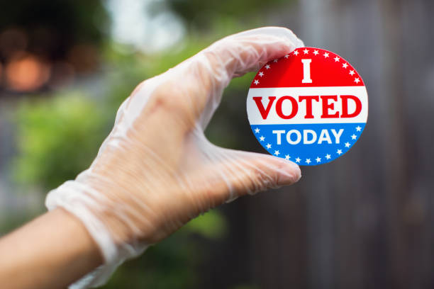 istock Hand wearing surgical glove holding I voted today sticker 1258005979