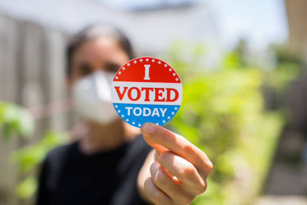 young woman wearing face mask holding i voted today sticker - jovens a votar imagens e fotografias de stock