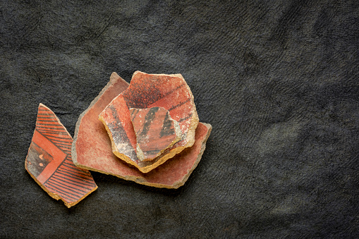 ancient Native American Indian (Anasazi) artifacts, several pottery fragments  on a dark paper background with a copy space
