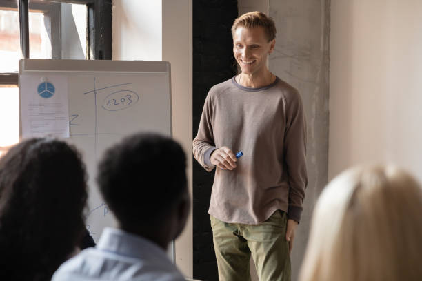 istock Smiling male trainer present project interact with colleagues at meeting 1258010034