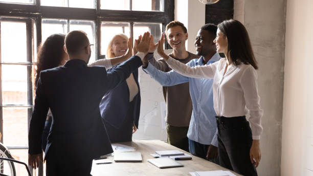 istock Overjoyed businesspeople give high five engaged in teambuilding activity 1258010043