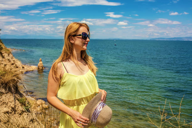 Smiling woman on the beach making call during her summer vacation