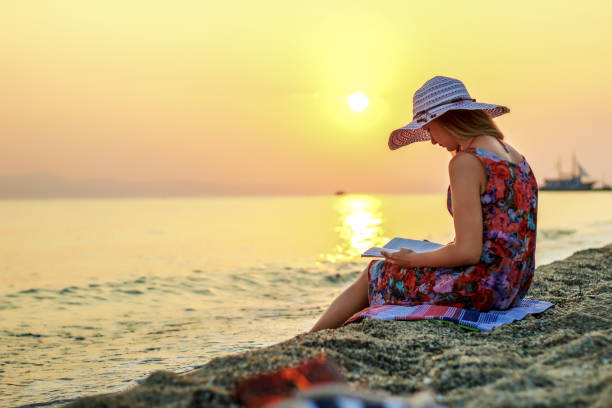 istock Woman Reading Book on Summer Beach Vacation 1258013843