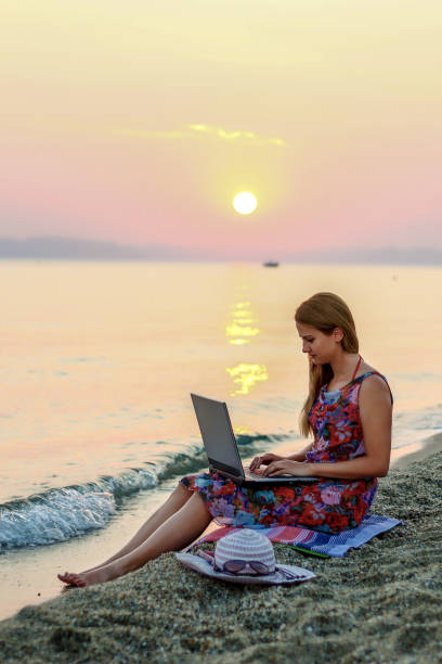 istock Young woman using laptop on the beach 1258013859