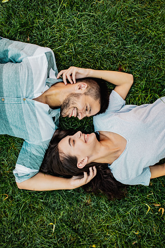 High angle view of young couple is laying in grass and looking at each other with love