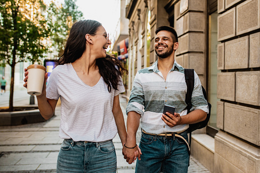Young couple in the city, holding hands and laughing