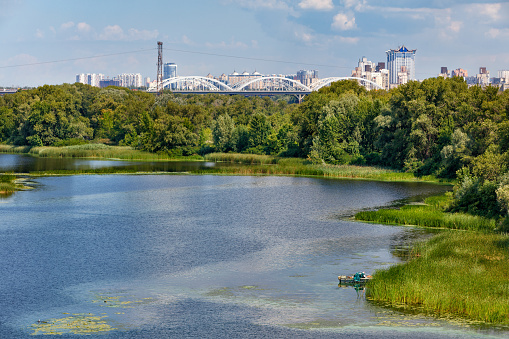 Natural picturesque landscape of the Dnieper bay near one of the river islands. An industrial city is visible in the background.