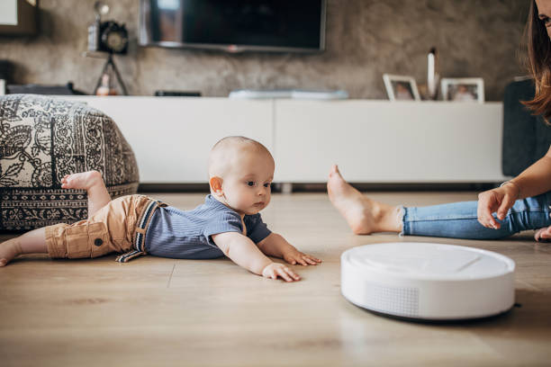 istock Young mother playing with her little son while robotic vacuum cleaner cleaning 1258021659