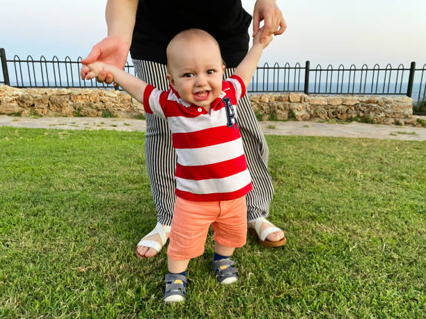 istock Confident baby learning to walk and mom helping him 1258023860