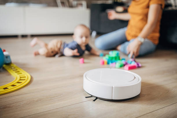 istock Mother playing with her baby son while robotic vacuum cleaner cleaning 1258023933