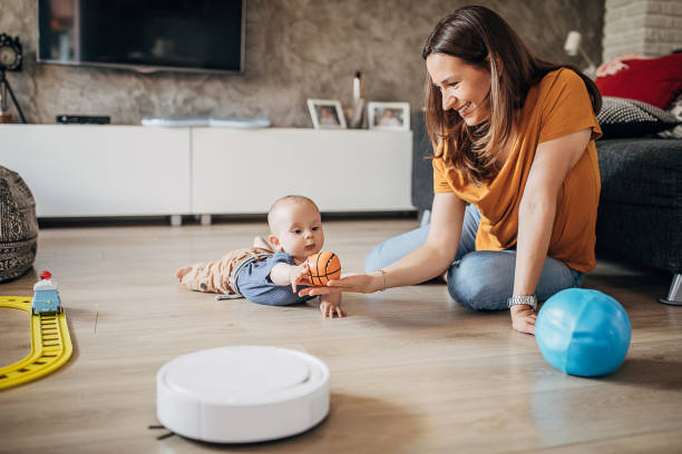 istock Mother and her baby son playing while robotic vacuum cleaner cleaning 1258024169